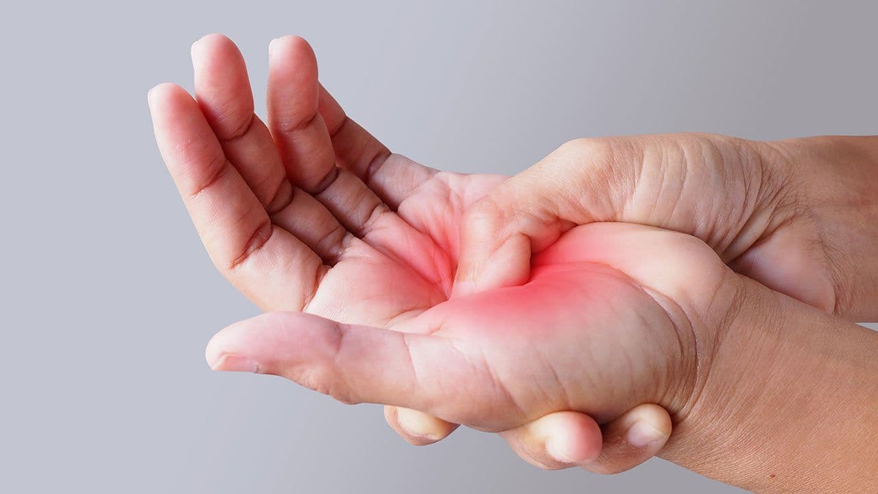 Person rubbing hand while using laptop